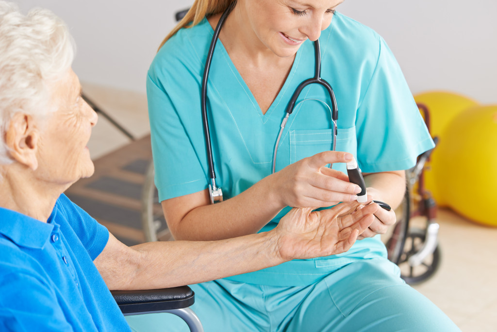 Nurse helping a senior on monitoring he blood sugar