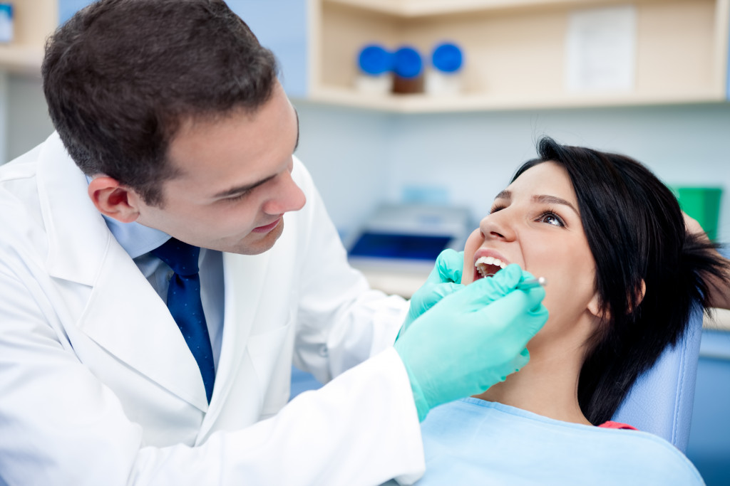 a young woman sitting in a dental chair getting checked by a dentist