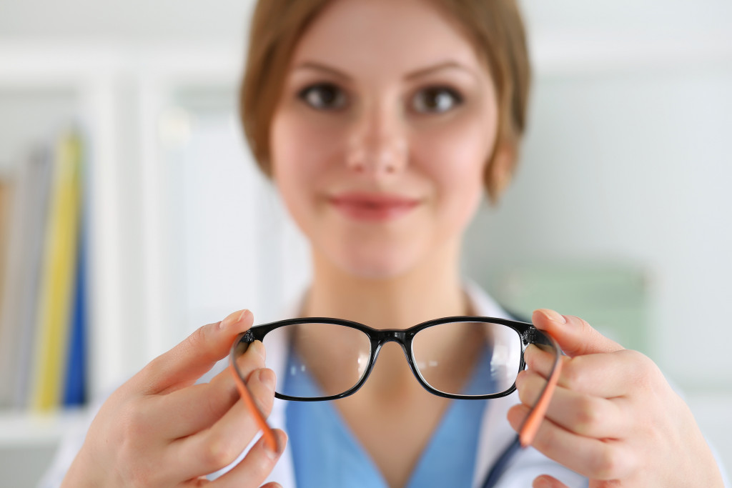 female optometrist handing person eyeglasses