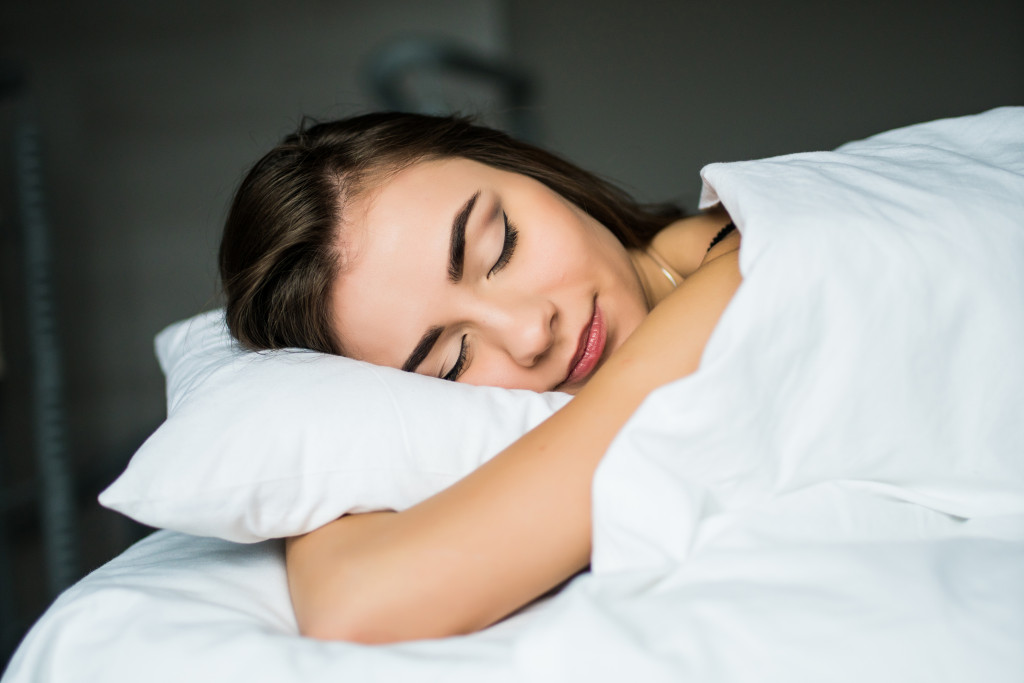 woman sleeping happily in all-white bed at home