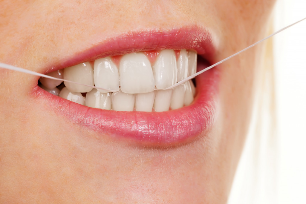 Young woman cleaning her teeth using dental floss.