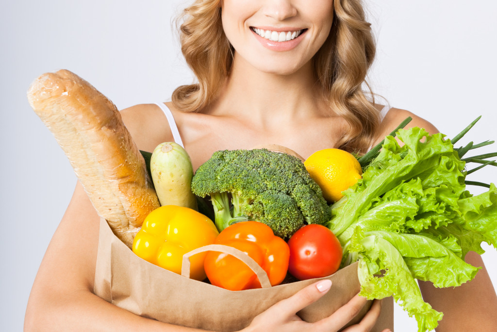 woman carrying paper bag full of healthy food and vegetables