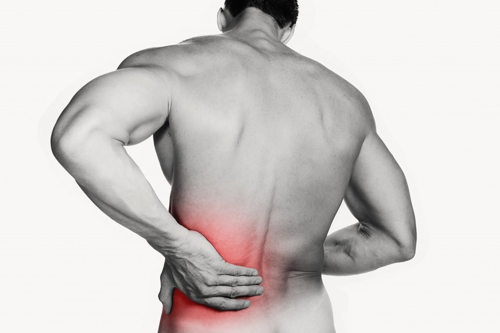 muscular topless man holding red back representing back pain