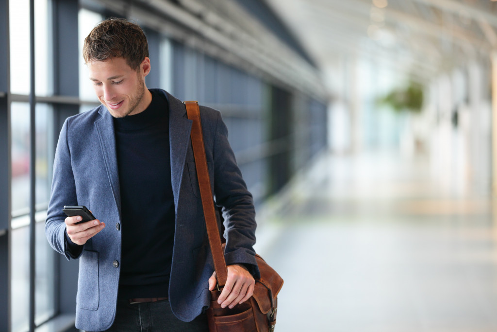 man wearing professional clothes walking home from airport using phone