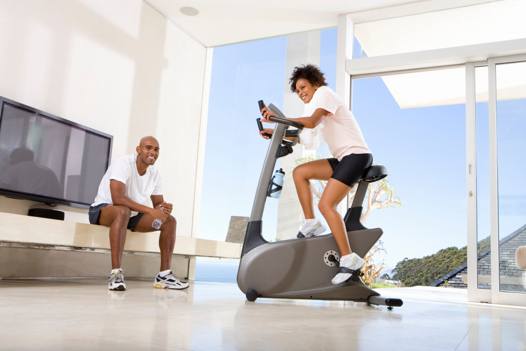 Couple exercising in the living room of their house using an exercise bike.