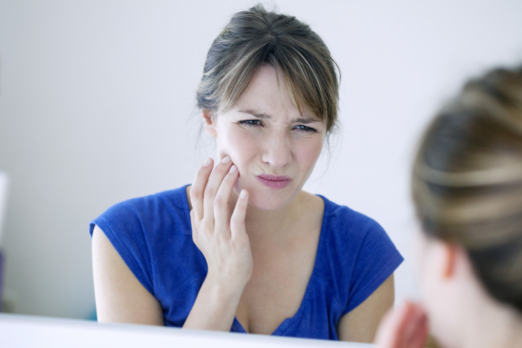 woman facing the mirror with tooth pain