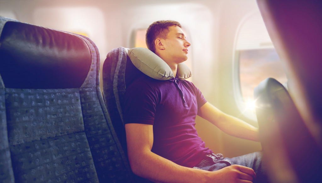 man sleeping on flight beside plane window