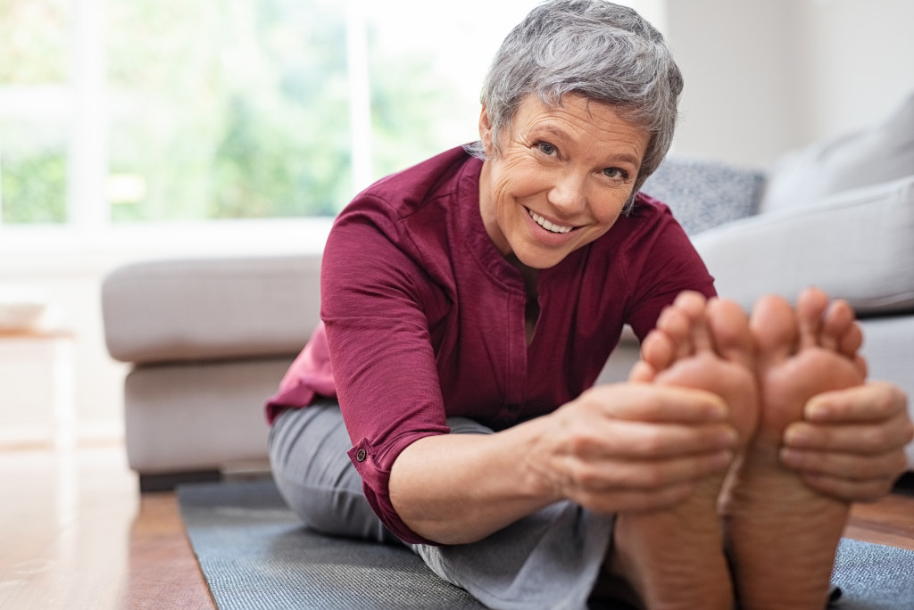 mature woman doing her stretches at home while looking at camera