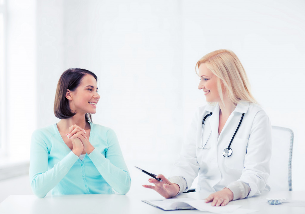 female patient smiling while talking to female doctor in all-white office