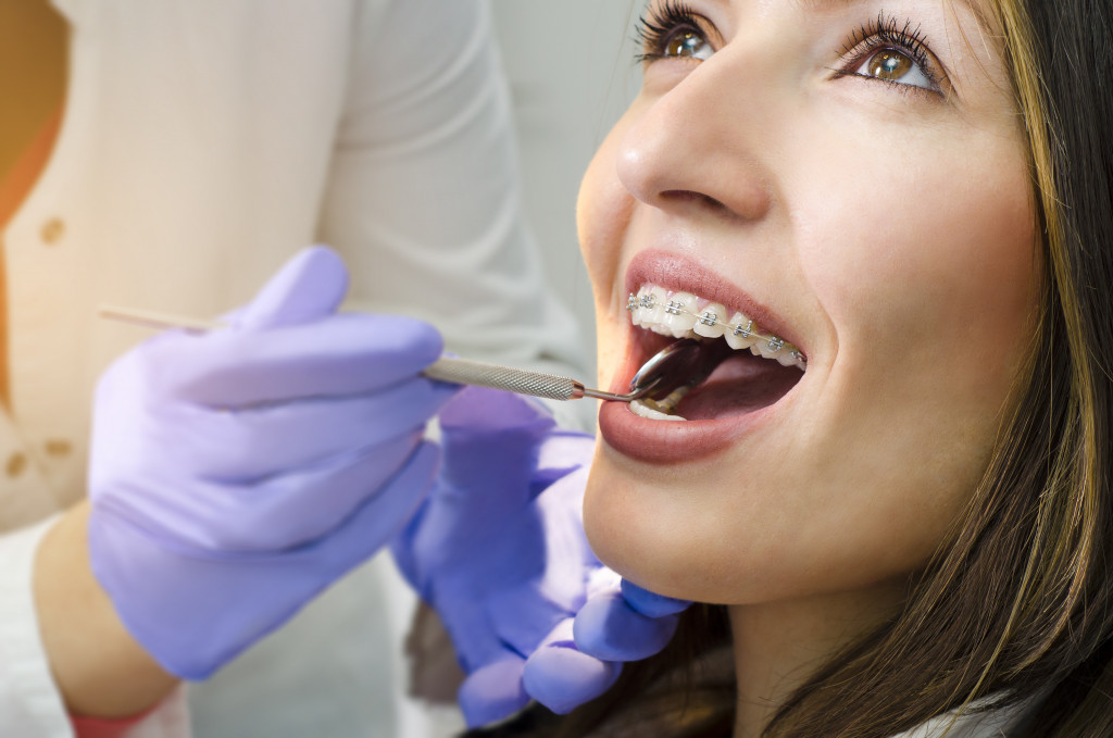 woman getting her teeth and braces checked by dentist