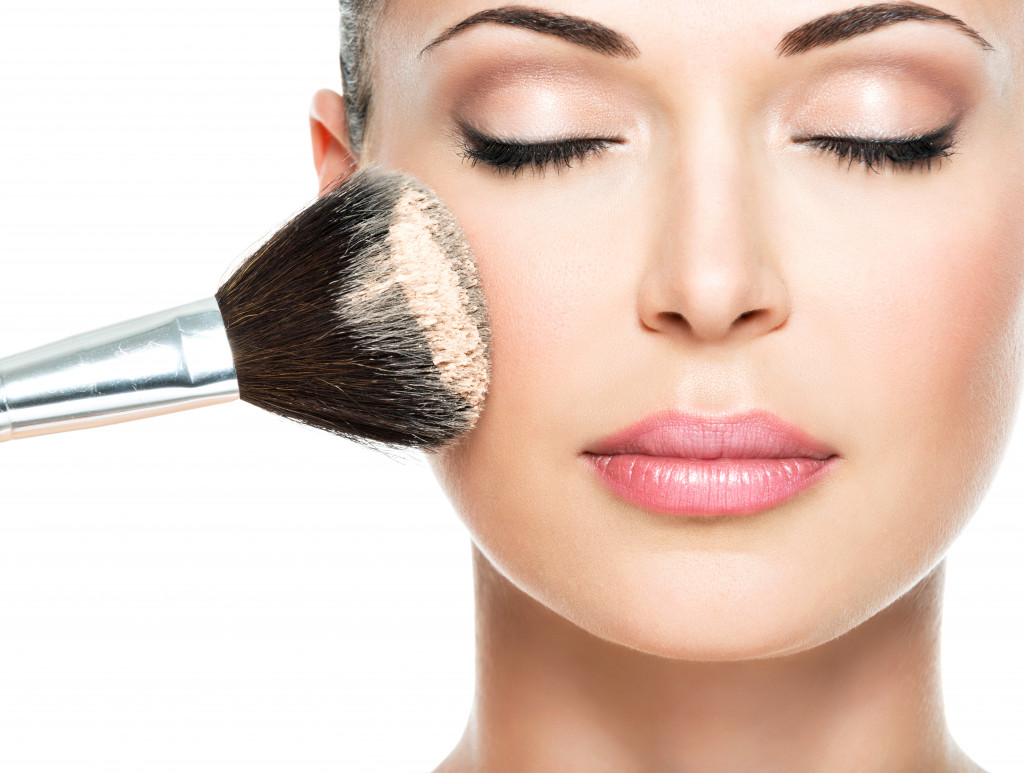 Closeup of a woman applying simple makeup using a makeup brush.