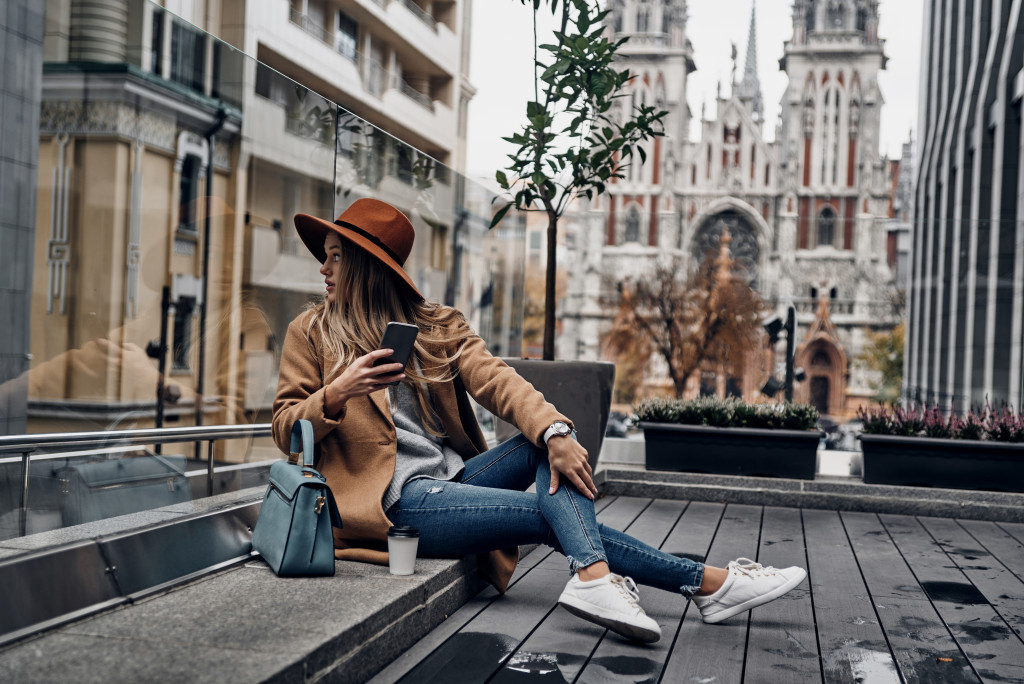 Young woman wearing timeless pieces while sitting on  bench.