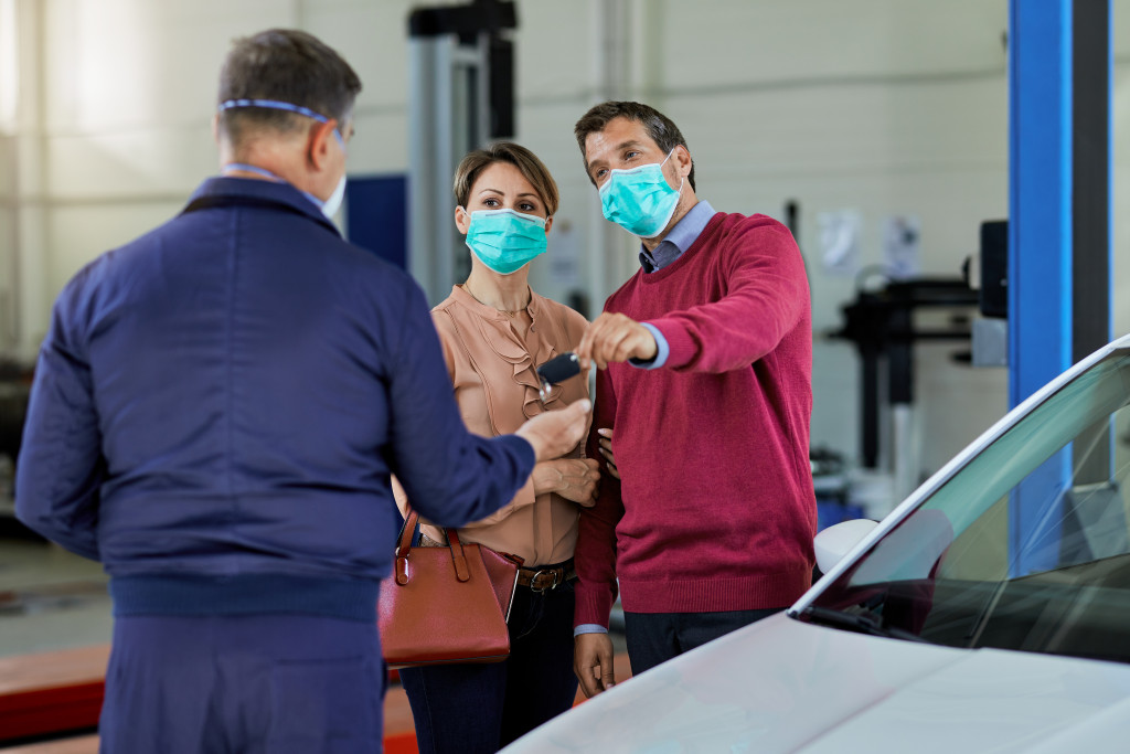 A couple wearing face masks while in an auto repair shop