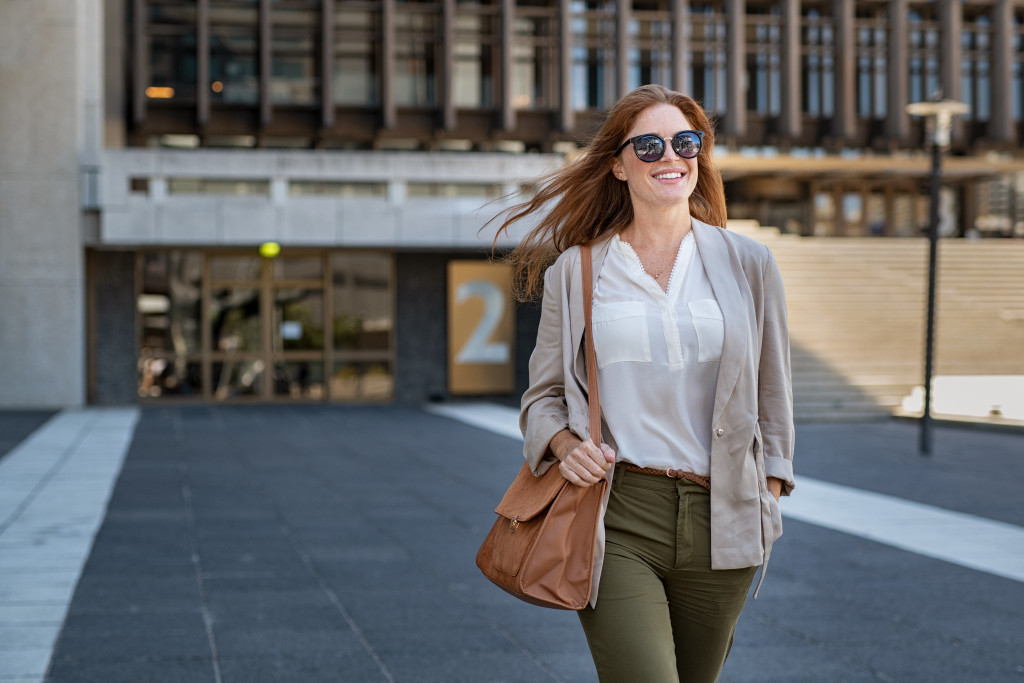 Smiling young woman walking on a street wearing a fashionable outfit.