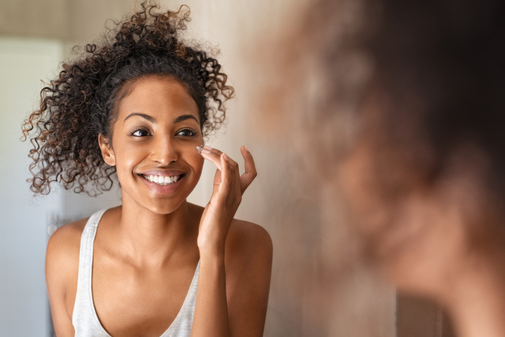 woman doing skin care in front of mirror