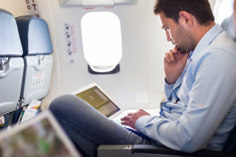 Young businessman using a laptop while on a plane.