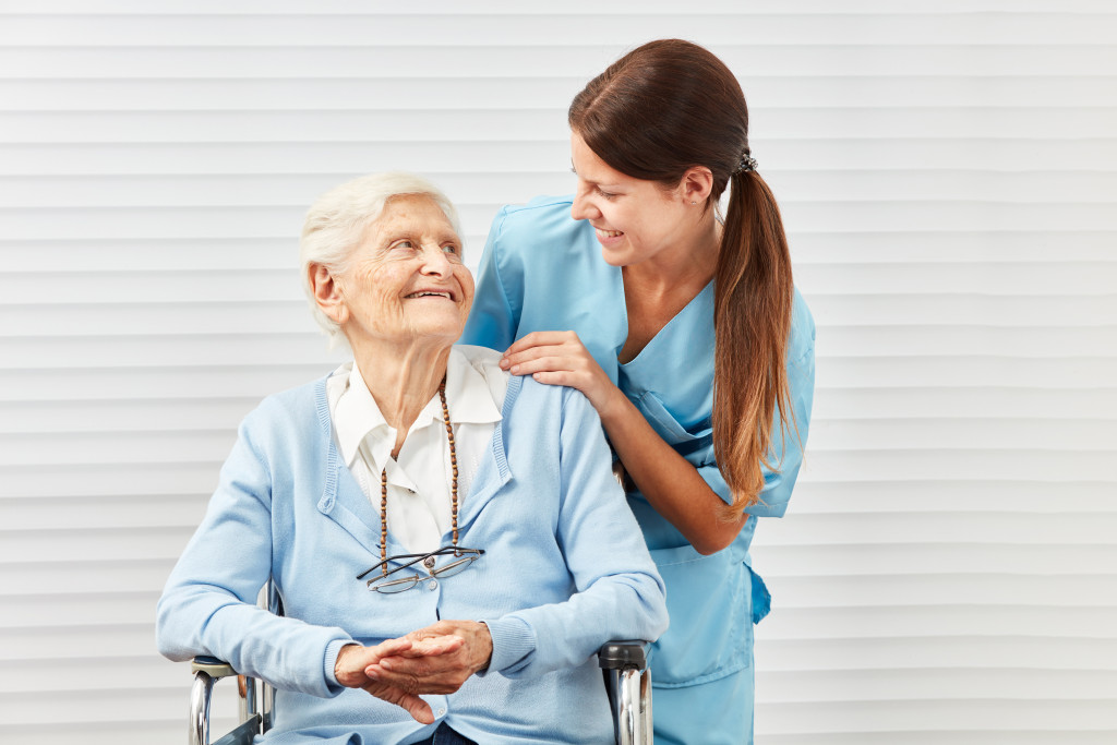 A caregiver smiling to a senior woman on a wheelchair