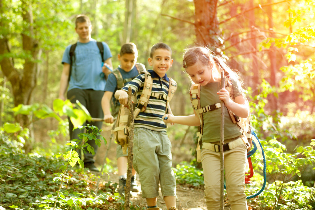 three kids hiking with their father in the woods in the daylight