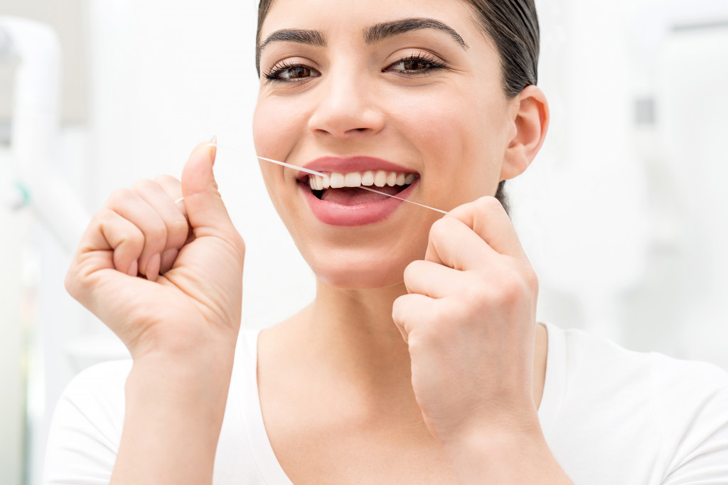 A woman flossing her teeth