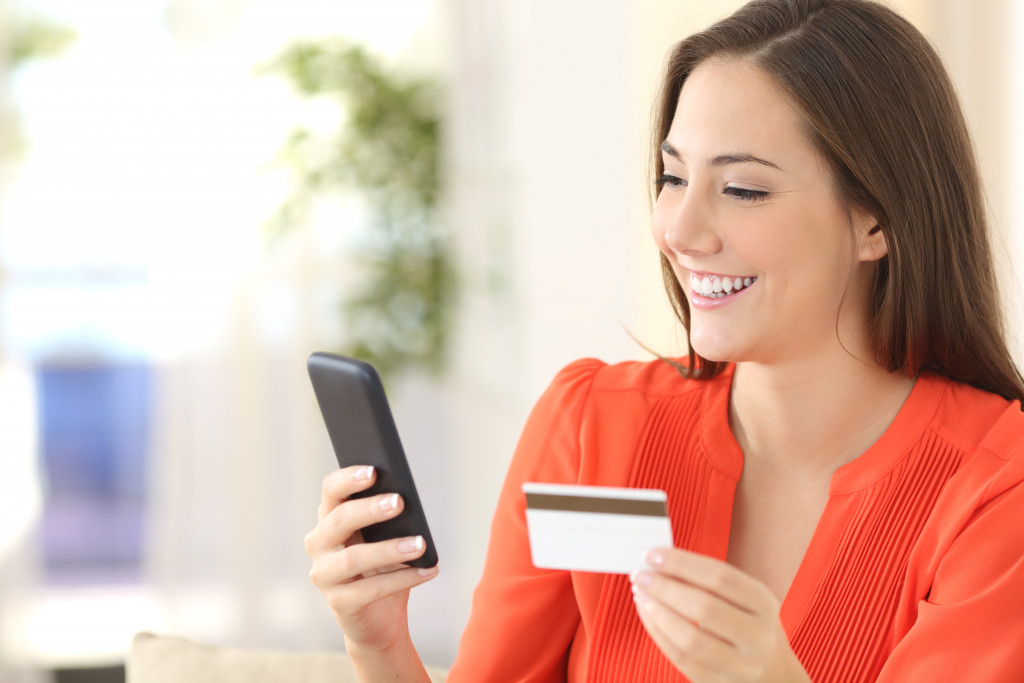 woman smiling while using phone for a budgeting app