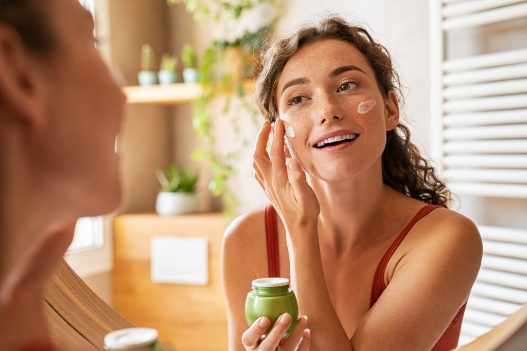 woman adding beauty cream to her face